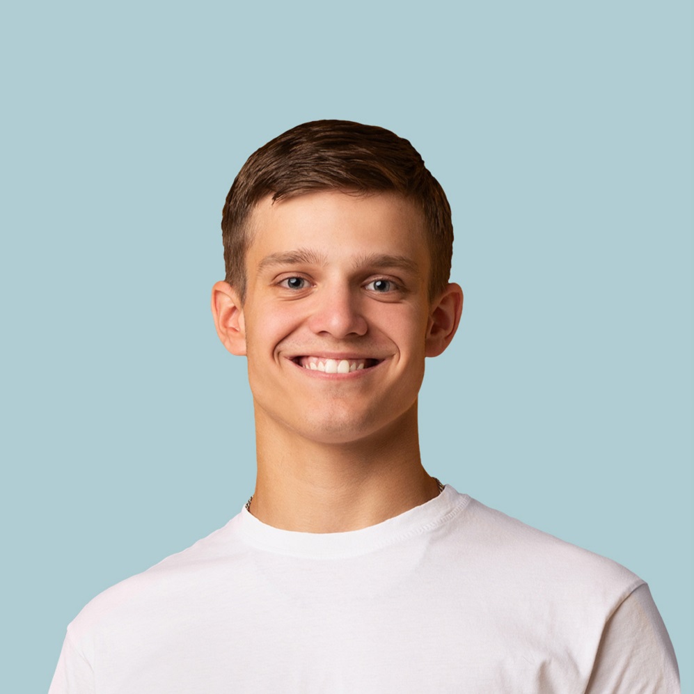 Smiling young man in a white T-shirt against a light blue background, facing the camera.